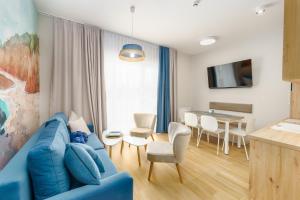 ein Wohnzimmer mit einem blauen Sofa und einem Tisch in der Unterkunft Sunset Resort II, Nadmorska 104 in Grzybowo
