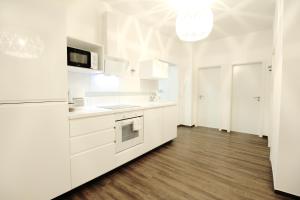 a white kitchen with white appliances and wooden floors at SECRET HIDEAWAYS Space Loft Wohndesign auf 2 Etagen l 450m bis Uni in Duisburg