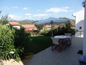un patio con sombrilla, mesa y sillas en Ktima Amitsa Studios & Apartments, en Sarti