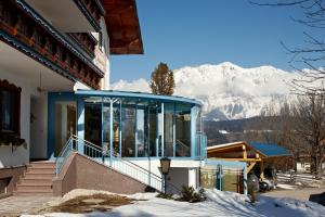 ein Haus mit einem Balkon mit Bergblick im Hintergrund in der Unterkunft Sportpension Alpenrose in Schladming