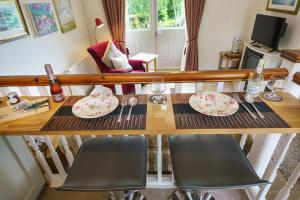 a wooden table with two chairs and plates on it at Penbontbren Luxury Bed and Breakfast in Aberporth