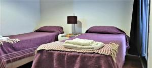 2 camas en una habitación con sábanas y toallas púrpuras en Dralas Cordoba-General Paz en Córdoba