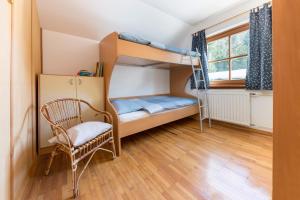 a bedroom with bunk beds and a chair and a window at Hiša nasproti sonca in Kranjska Gora
