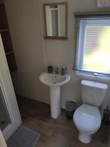 a bathroom with a white toilet and a sink at Lovely Static 8 Bed Caravanat at Billing Aquadrome in Great Billing