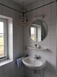 ein weißes Badezimmer mit einem Waschbecken und einem Spiegel in der Unterkunft Ferienhaus Poseidon in Neuharlingersiel
