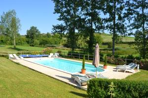 a swimming pool with two chairs and an umbrella at Manoir La Breuille in Montmoreau