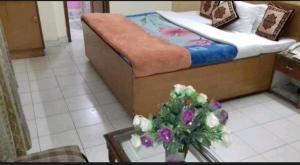 ein Schlafzimmer mit einem Bett und einem Tisch mit einer Blumenvase in der Unterkunft Sunrise hotel in Jalandhar