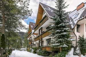 a building with a snow covered tree in front of it at Rent like home - Arkadia pod Nosalem in Zakopane