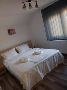 a bedroom with a white bed with two towels on it at Viata la Tara Cerna in Cerna