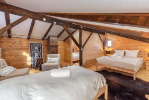 een slaapkamer met 2 bedden en stoelen op een zolder bij Chalet Noisette Authentic Swiss chalet Perfect for families in La Tzoumaz