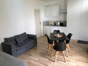 ein Wohnzimmer mit einer Couch und einem Tisch und Stühlen in der Unterkunft L'orée du Golf, studio 4 in Mont-Saint-Aignan