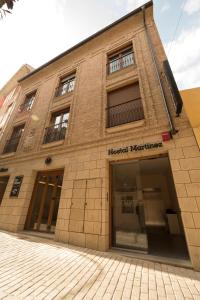 un edificio in mattoni su una strada con un negozio di Hostal Martínez a Villafranca