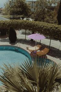 a swimming pool with two chairs and an umbrella at Nonna's Boutique Hotel in Dhërmi
