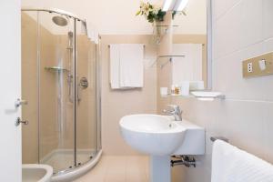 biała łazienka z umywalką i prysznicem w obiekcie Contempora Apartments - Elvezia 8 - E52 w Mediolanie +18 zdjęć
