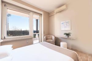 sypialnia z łóżkiem, oknem i krzesłem w obiekcie Contempora Apartments - Elvezia 8 - E52 w Mediolanie