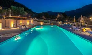 a swimming pool at night with chairs and tables at Lavanda e Pietra in Lygourio