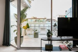 ein Wohnzimmer mit einem TV und einem großen Fenster in der Unterkunft Acropolis Veranda Residence in Athen