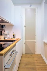 a kitchen with white cabinets and a wooden floor at Viihtyisä & Varusteltu Keskusta-asunto Neljälle! in Tampere