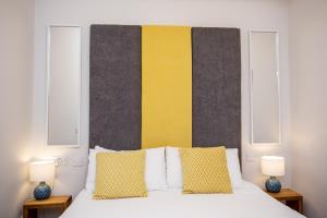 a bedroom with a bed with a yellow and black headboard at Stay Coastal in Whitley Bay