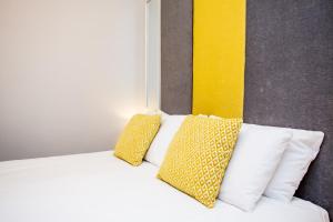 a bed with yellow and white pillows on it at Stay Coastal in Whitley Bay