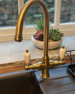 a kitchen sink with a gold faucet at Cross Haw Cottage in Sedbergh