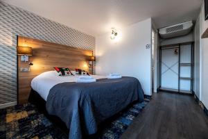 Un dormitorio con una cama grande en una habitación. en Hôtel Le Cyrano Bergerac, en Bergerac