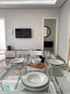 a dining room with a table with plates and silverware at Le Safran - apt renove, spacieux et central a Marsa in Carthage