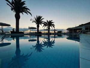 una gran piscina con palmeras en el fondo en Paradise Beach Apartments en Argasi