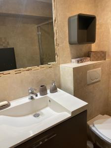 uma casa de banho com um lavatório e uma televisão na parede em Beach-studio em Antibes