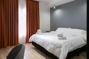 Buongiorno B&B Hotel في ماركوس خواريز: غرفة نوم بسرير ابيض كبير وكرسي