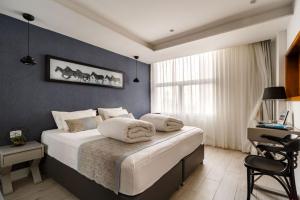 a bedroom with a bed and a desk in a room at Kikar Boutique Hotel in Netanya