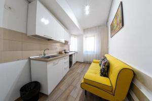 a yellow couch in a kitchen with a sink at Avenue Parliament Old Town - Avenue Hotels in Bucharest