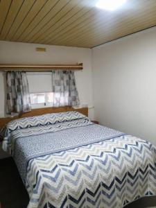 Schlafzimmer mit einem Bett mit einer blauen und weißen Bettdecke in der Unterkunft House Camping Pasito Blanco in Maspalomas