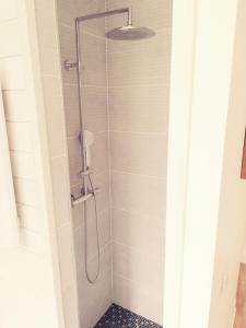 a shower with a glass shower head in a bathroom at Suite 24 Appart'hôtel-3 étoiles in Le Creusot