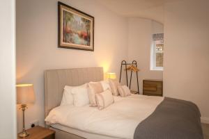 a bedroom with a bed with white sheets and pillows at Ravelston Grange - stylish, spacious garden flat in Old Town