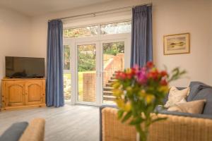a living room with a sliding glass door with a television at Ravelston Grange - stylish, spacious garden flat in Old Town