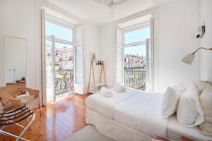 - une chambre blanche avec un grand lit et de grandes fenêtres dans l'établissement Downtown Apartments, à Lisbonne