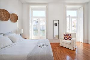 - une chambre blanche avec un lit blanc et une chaise dans l'établissement Downtown Apartments, à Lisbonne