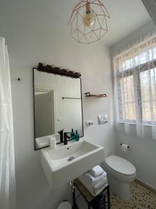 a bathroom with a sink and a toilet and a mirror at Macallè Suite Noto, charme e relax con giardino in Noto