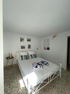 a bedroom with a white bed with blue and white pillows at Macallè Suite Noto, charme e relax con giardino in Noto