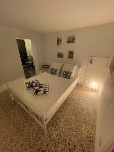 a bedroom with a white bed with black and white pillows at Macallè Suite Noto, charme e relax con giardino in Noto