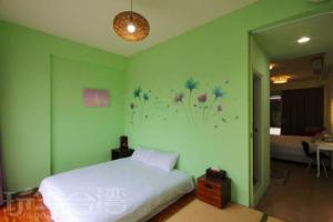 a green bedroom with a bed and flowers on the wall at Sanyi Dream Garden B&B in Sanyi
