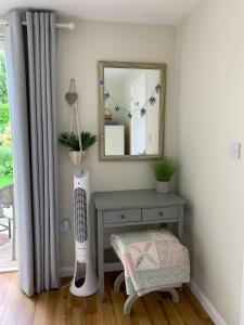 a room with a mirror and a table with a fan at New Forest Chalet in Ibsley