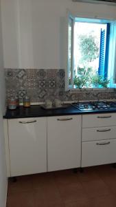 a kitchen with white cabinets and a window at Appartamenti La Villa Peschici in Peschici