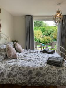 a bed in a bedroom with a large window at New Forest Chalet in Ibsley