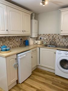 a kitchen with white cabinets and a washer and dryer at New Forest Chalet in Ibsley +24 photos