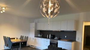a kitchen with white cabinets and a table and a chandelier at Ferienwohnung am Tor zum Thüringer Wald in Plaue