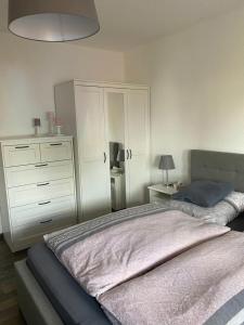 ein Schlafzimmer mit einem Bett, einer Kommode und einem weißen Schrank in der Unterkunft Ferienwohnung am Tor zum Thüringer Wald in Plaue