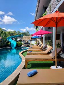 a pool with chairs and umbrellas and a slide at Samui Zenity in Mae Nam