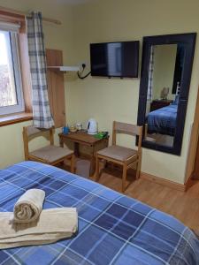 a bedroom with a bed, chair, desk and a mirror at Hamnavoe B&B in John O Groats